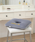 Gray donut pillow with 'Be Happy' text on a white chair in front of a vanity table.