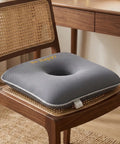 Gray donut cushion on a wooden chair with a desk in the background
