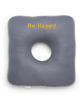 Gray square cushion with a circular hole and 'Be Happy' text on a white background