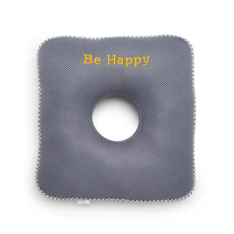 Gray square cushion with a circular hole and 'Be Happy' text on a white background