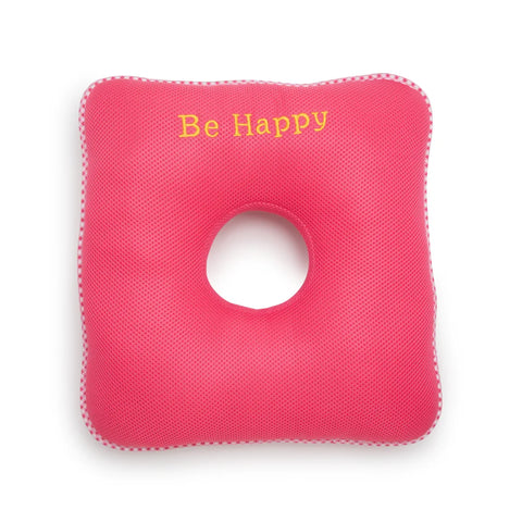 Pink square donut cushion with a circular hole and 'Be Happy' text on a white background