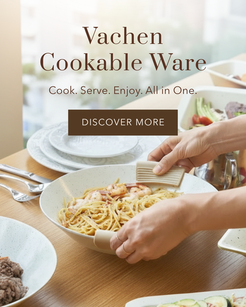 A person's hands use a beige silicone pot holder to serve spaghetti from a speckled cream-colored bowl on a wooden dining table. The image features text overlays reading 'Vachen Cookable Ware'.