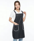 Woman wearing a black apron with white trim on a white background