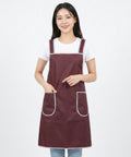 Woman wearing a maroon apron with white trim on a white background