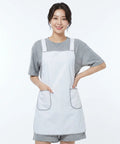 Person wearing a white apron over a gray outfit on a white background