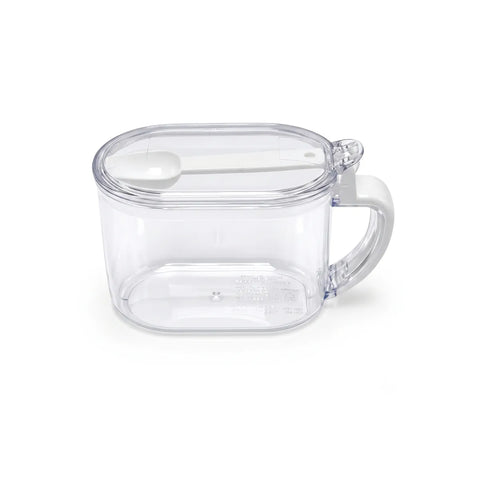 A clear plastic measuring cup with a white handle and a white measuring spoon inside, shown on a plain white background.