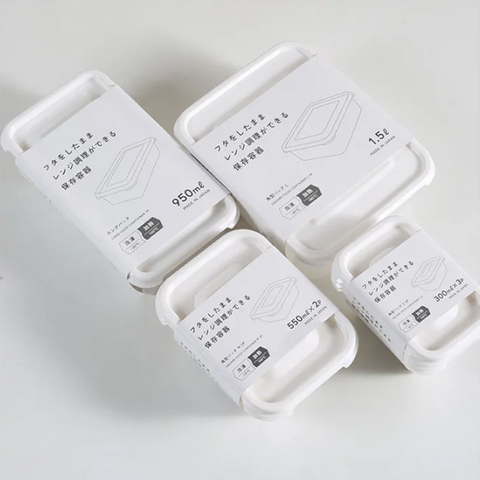 Four white plastic storage containers with lids, each wrapped in a white paper sleeve with Japanese text and size markings (950ml, 1.5L, 550ml 2-piece, 300ml 2-piece), arranged on a light gray background.