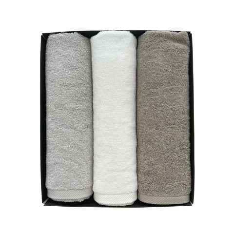 Three folded towels in gray, white, and beige in a black box on a white background