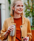Woman holding a stainless steel water bottle outdoors