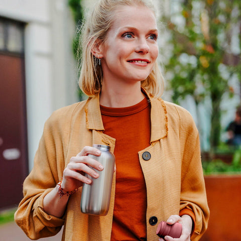 Woman holding a stainless steel water bottle outdoors