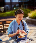 Woman sitting at a picnic table eating outdoors