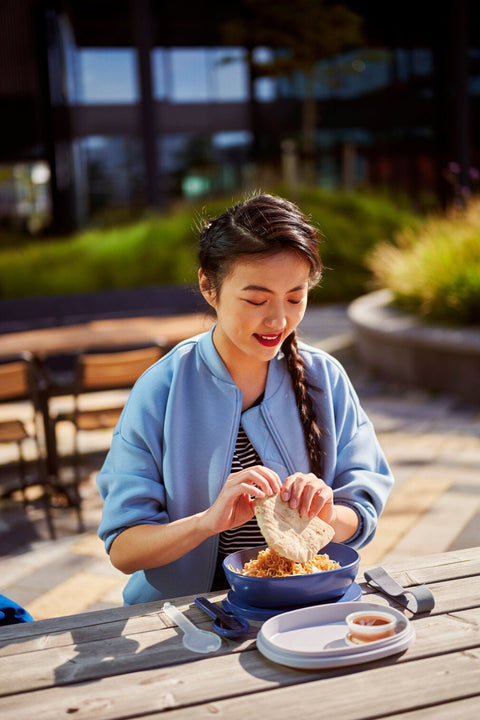 Woman sitting at a picnic table eating outdoors