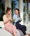 Two women sitting on a porch, enjoying a meal together.