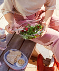 Person holding a salad bowl with a wooden table and water bottle in the background