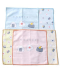 Three square microfiber dish cloths with onigiri illustrations, arranged in a grid on a white background. The top cloth is light blue, the middle-left is pale yellow, and the center is a soft pink with peach edging.