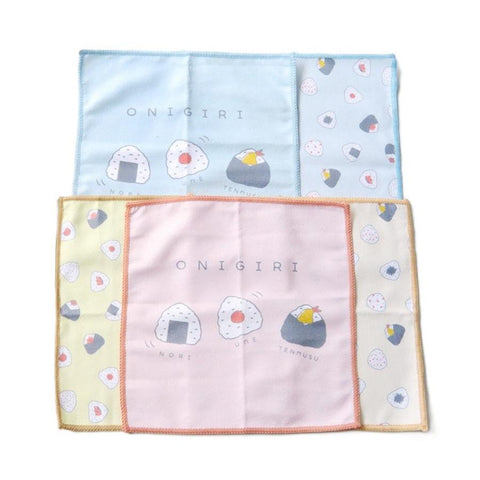 Three square microfiber dish cloths with onigiri illustrations, arranged in a grid on a white background. The top cloth is light blue, the middle-left is pale yellow, and the center is a soft pink with peach edging.